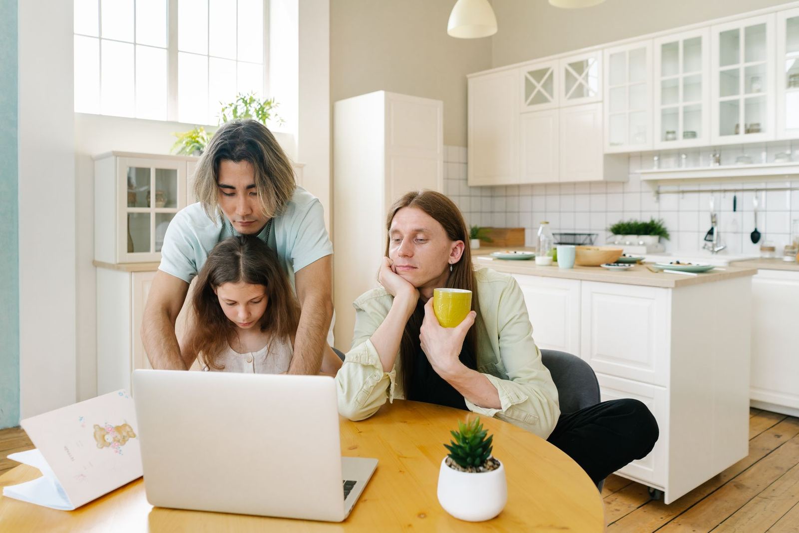 A family at a kitchen table looking at a laptop together