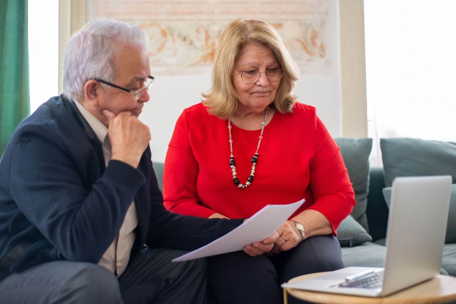 An older couple reviewing plan papers together beside a laptop